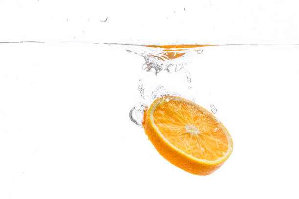rodaja de naranja en salpicaduras de agua. fondo blanco - splashing orange fruit water fotografías e imágenes de stock