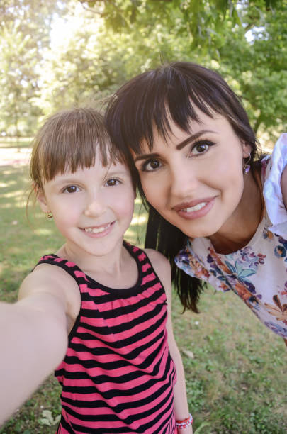 Mother and daughter take selfie in park