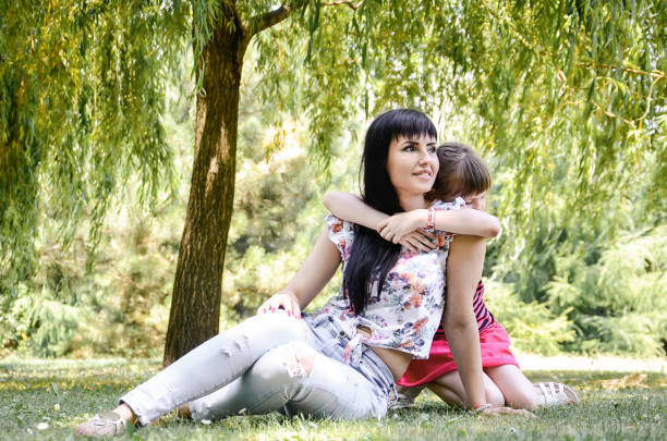 istock Mother and daughter sit on the grass 803944232