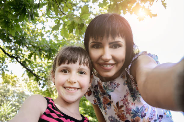 istock Mother and daughter take selfie in park 803944266