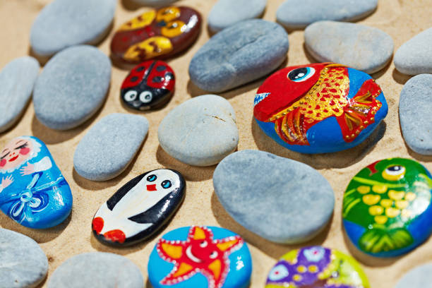 Rounded colorful stones pebbles shingle with pictures painted on them stock photo