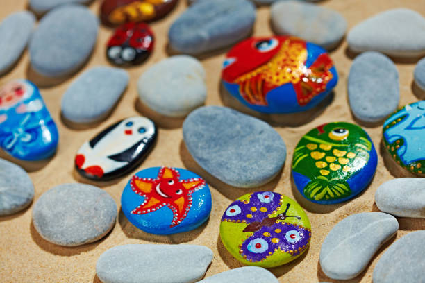 istock Rounded colorful stones pebbles shingle with pictures painted on them 803944524