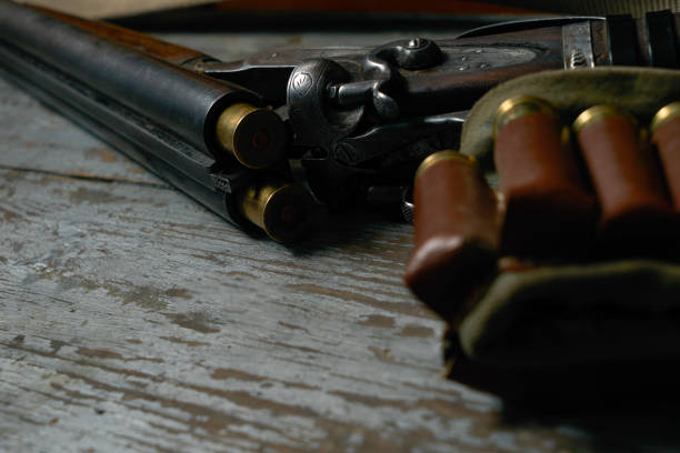 istock Double-barreled Long gun riffle on a wooden table with ammo. 803949954