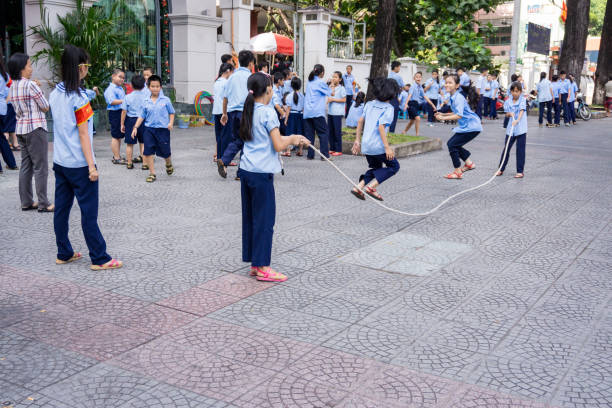 A diverse group of children pulls a rope in a friendly tug-of-war across a grassy field, showcasing teamwork, outdoor activity, and playful competition among friends.