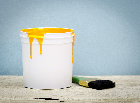 White plastic bucket with yellow color paint and brush on wood,vintage background