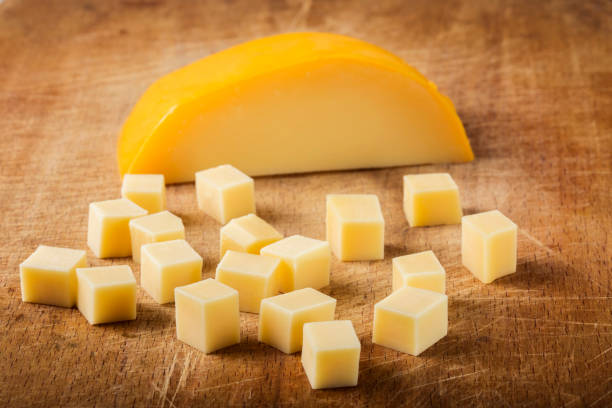 Cubes of yellow cheese stacked randomly Cubes of yellow cheese stacked randomly on wooden chopping board colby cheddar stock pictures, royalty-free photos & images