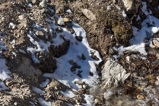 Snow on the ground with clay, grass and stone at Lachen. North Sikkim, India.