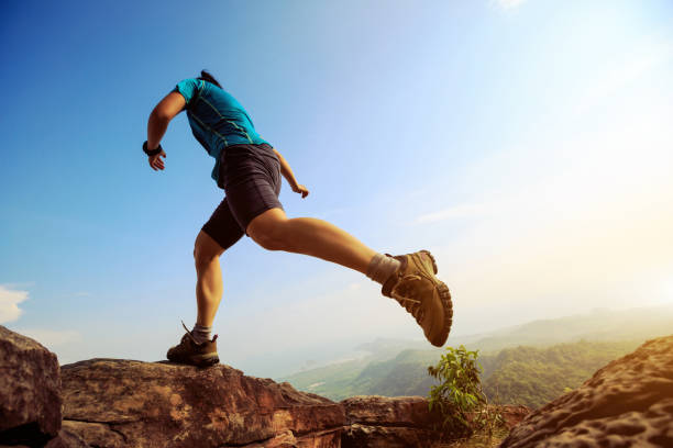 istock Young woman running and jumping on mountain peak 804040234