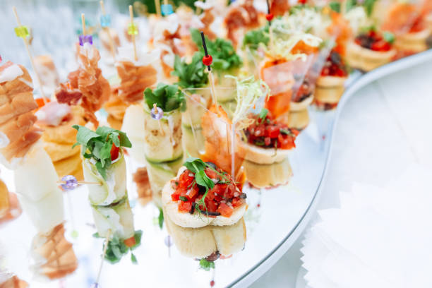 Beautifully decorated catering banquet table with different food snacks and appetizers Beautifully decorated catering banquet mirror  table with different food snacks and appetizers caterer photos stock pictures, royalty-free photos & images