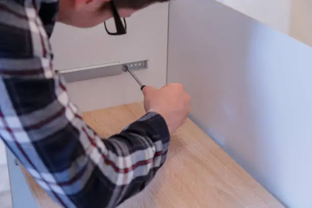 Young man assembles furniture