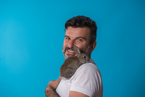 Portrait of a happy men with rabbit  over colored background.