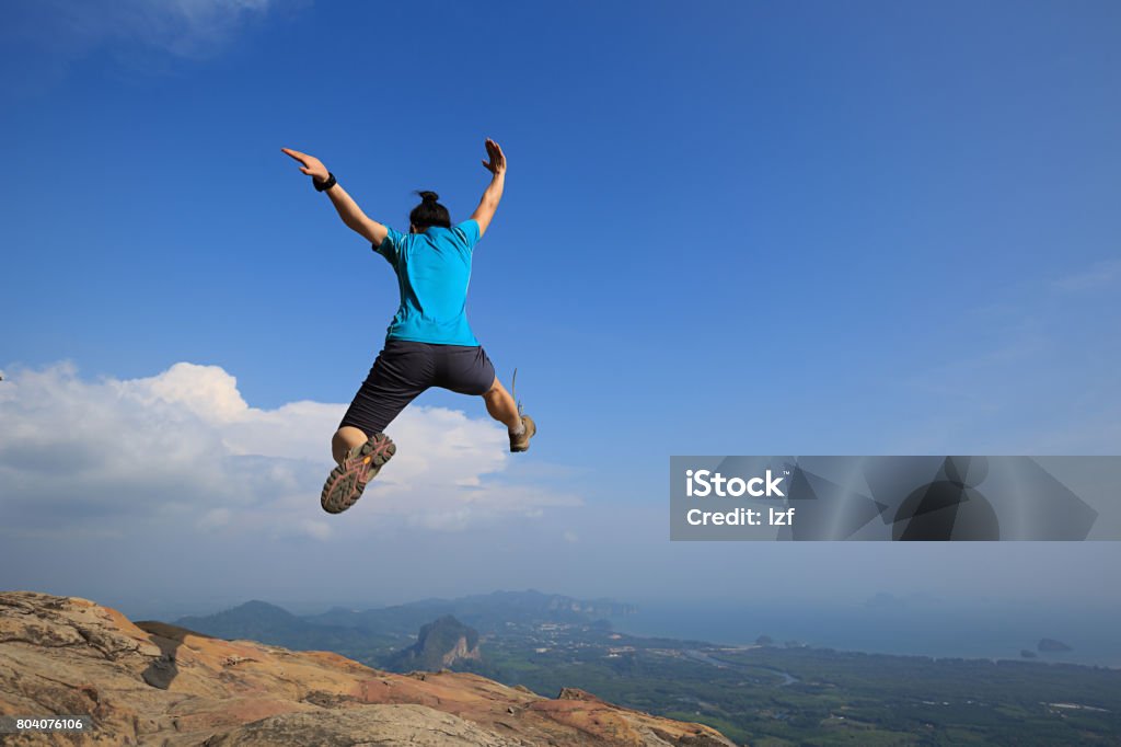 Young woman jumping on mountain peak Achievement Stock Photo