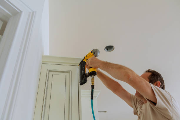 istock Carpenter brad using nail gun to Crown Moulding on kitchen cabinets framing trim, 804157278