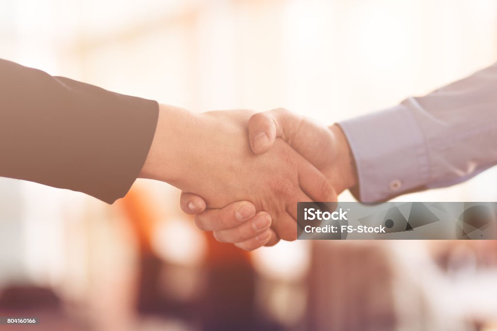 People at work: man and woman hand shaking at a meeting People at work: man and woman hand shaking at a meeting. Gripping Stock Photo