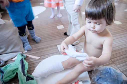 Child wearing clothes in kindergarden, white socks in kids hands
