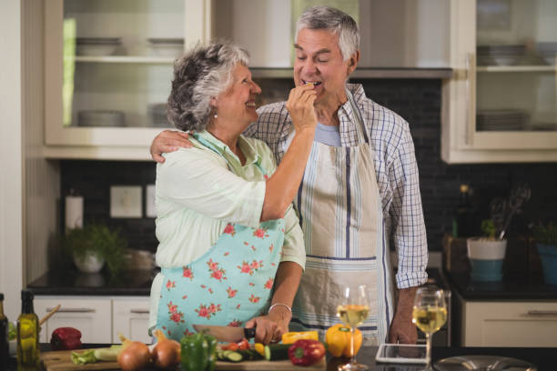 istock Smiling senior woman feeding man while standing in kitchen 804170710