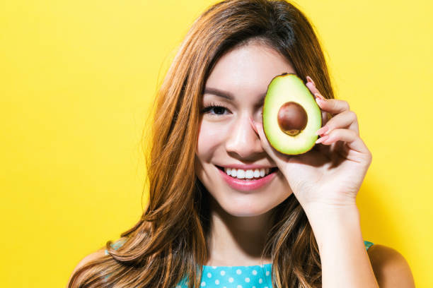 istock Happy young woman holding avocado halve 804177992