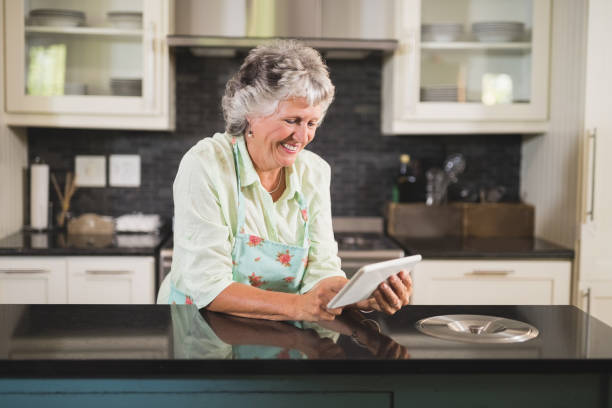 istock Smiling senior woman using digital tablet in kitchen 804193808