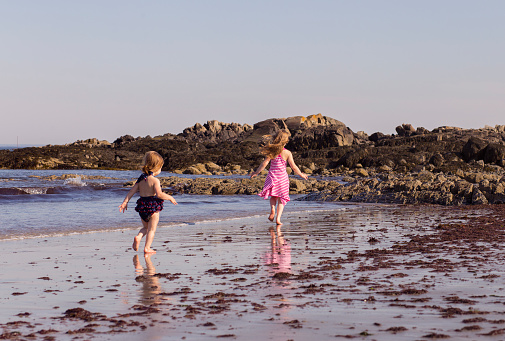 Two sisters enjoying the beach and running around.