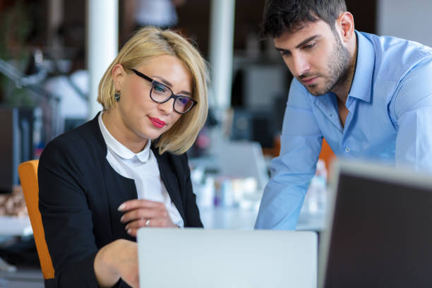 istock Colleagues chatting, sitting together at office table, smiling 804223130
