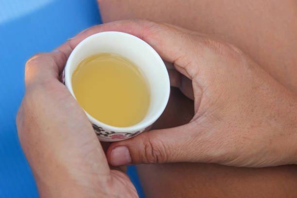 White ceramic cup on saucer with refreshing herbal tea, accompanied by a glass pitcher, set on a patterned tablecloth in a serene outdoor cafe environment