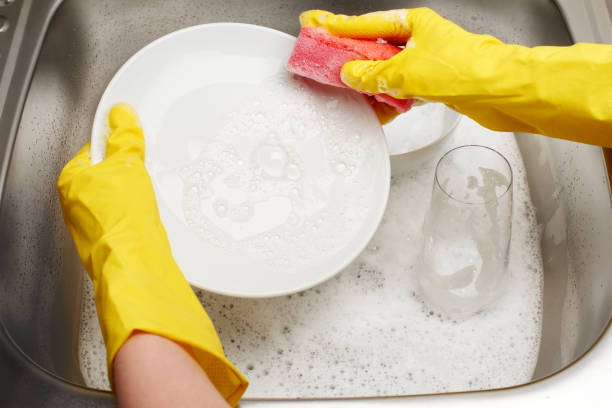 istock Hands in gloves washing white plate with pink cleaning sponge 804250210