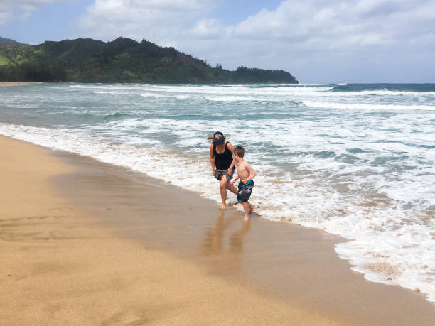 istock mother and son play together in the waves 804251028