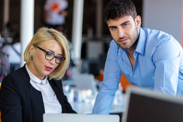 istock Colleagues chatting, sitting together at office table, smiling 804253630