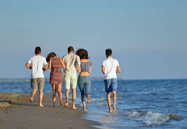 istock Group of friends having fun walking down the beach at sunset 804257382