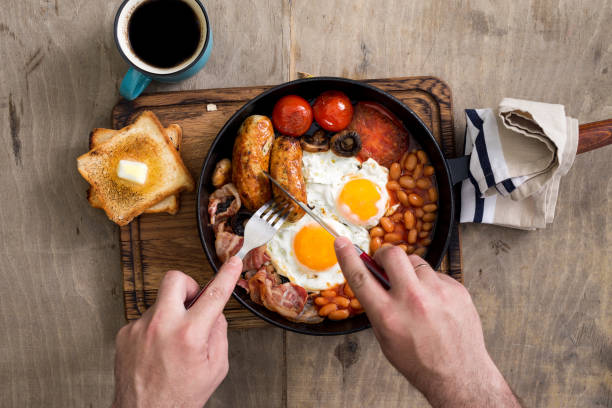 istock Man is eating English breakfast on a wooden light table 804259942