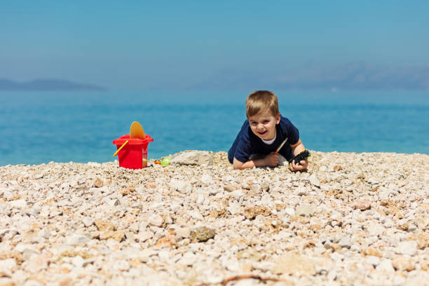 bambino sorridente seduto su una roccia con paesaggio marino sullo sfondo - student outdoors clothing southern africa foto e immagini stock