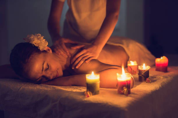 A portrait of two young attractive woman lie on bed during having back massage by a professional masseur at outdoor surrounded by peaceful natural environment. Healthy and beauty concept. Tranquility.