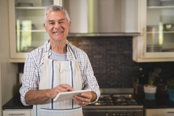 istock Smiling senior man using digital tablet in kitchen at home 804295602