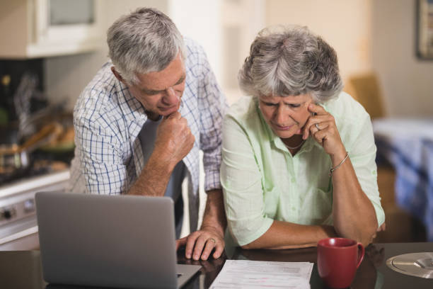 istock Serious senior cpouple reading documents by laptop on table 804295800