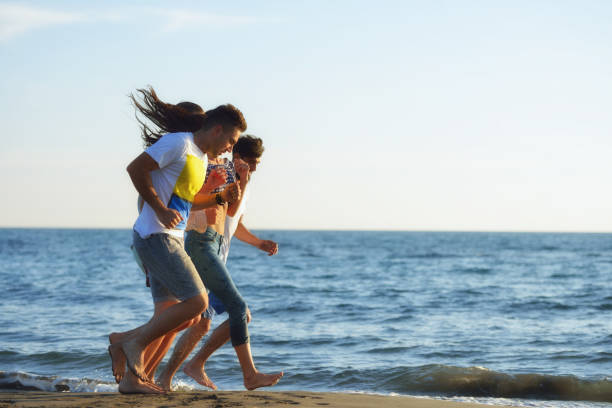 istock Group of friends having fun walking down the beach at sunset 804298834