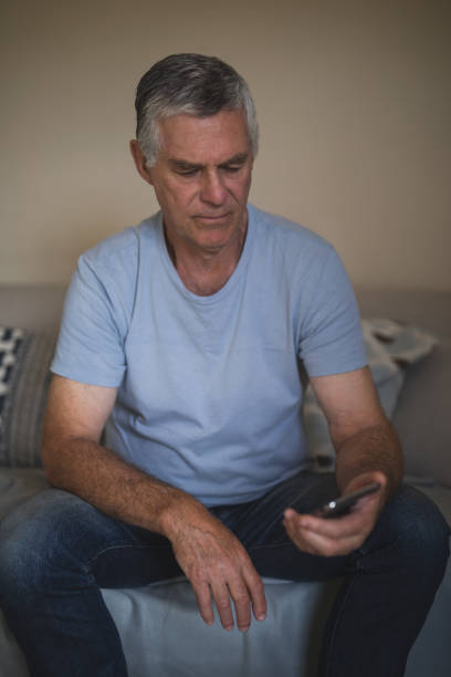 istock Upset senior man holding mobile phone while sitting on sofa 804305128