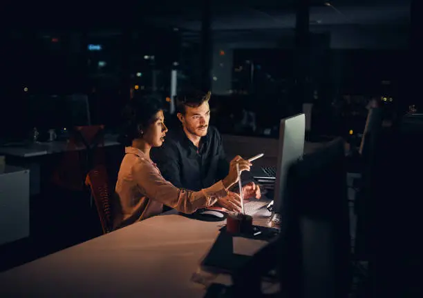 Shot of two businesspeople working late in an office