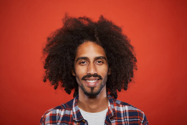 Studio headshot of young trendy spanish man. Studio headshot of young trendy spanish man. Plain background. Mixed reace model with curly hair. afro man stock pictures, royalty-free photos & images