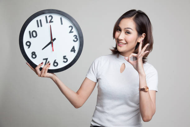 istock Young Asian woman show OK with a clock. 804358822