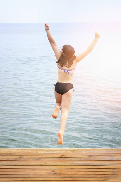 istock Girl jumping into the sea 804359042