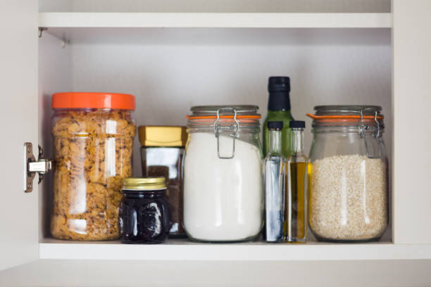 food cupboard, pantry with jars stocked kitchen pantry with food - jars and containers of cereals, jam, coffee, sugar, flour, oil, vinegar, rice rice food staple photos stock pictures, royalty-free photos & images