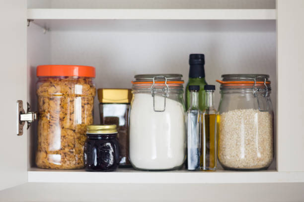 food cupboard, pantry with jars stocked kitchen pantry with food - jars and containers of cereals, jam, coffee, sugar, flour, oil, vinegar, rice rice food staple stock pictures, royalty-free photos & images