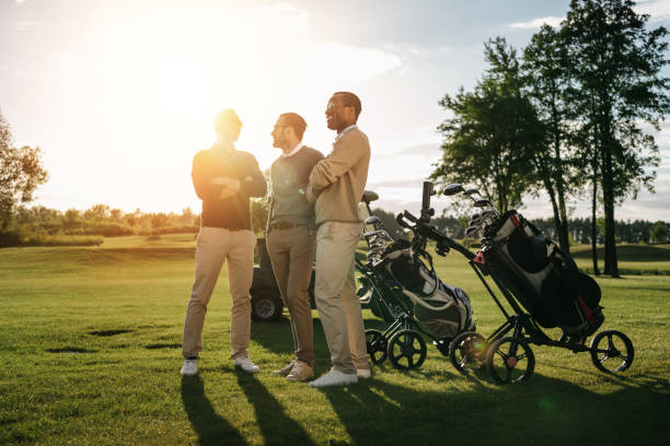 trzech uśmiechniętych mężczyzn stojących ze skrzyżowanymi ramionami w pobliżu kijów golfowych w workach - golf bag zdjęcia i obrazy z banku zdjęć