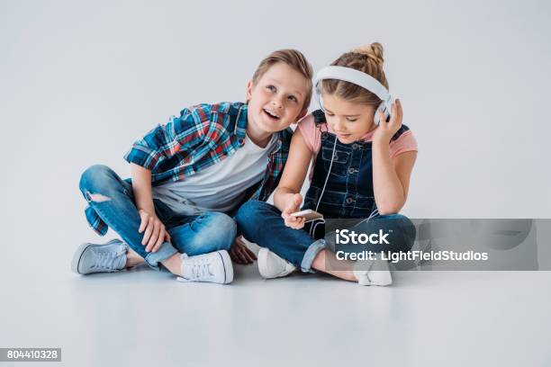 Photo libre de droit de Enfants Adorables Lécoute De La Musique Au Casque Tout En Étant Assis Sur Le Sol banque d'images et plus d'images libres de droit de 8-9 ans