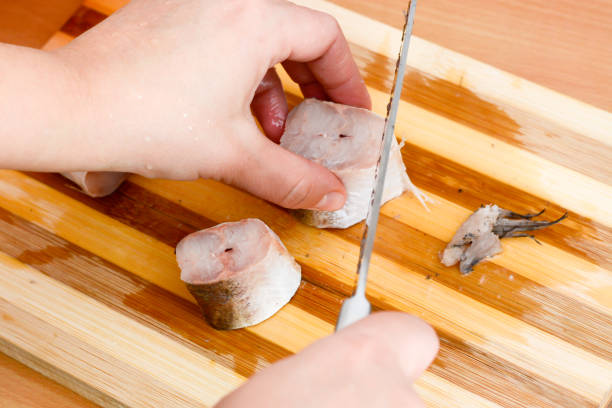 istock Female hands with knife slicing fish hake 804423866