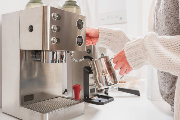 Woman steaming milk for cappuccino on professional espresso machine Woman frothing milk for cappuccino using steam pressure on professional espresso machine espresso maker stock pictures, royalty-free photos & images