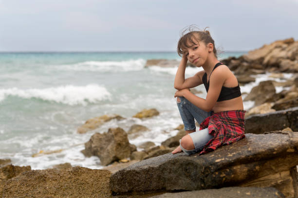 Little girl sitting on the rocks of a creek of Villajoyosa, in the province of Alicante, Spain.\