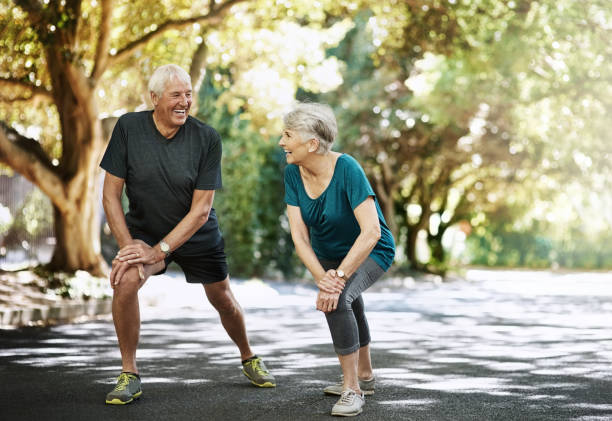 Boosting their long-term wellbeing together Shot of a senior couple warming up before a run outside warming up stock pictures, royalty-free photos & images