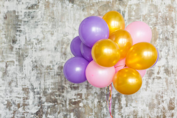 Bright balloons bunch against a textured wall