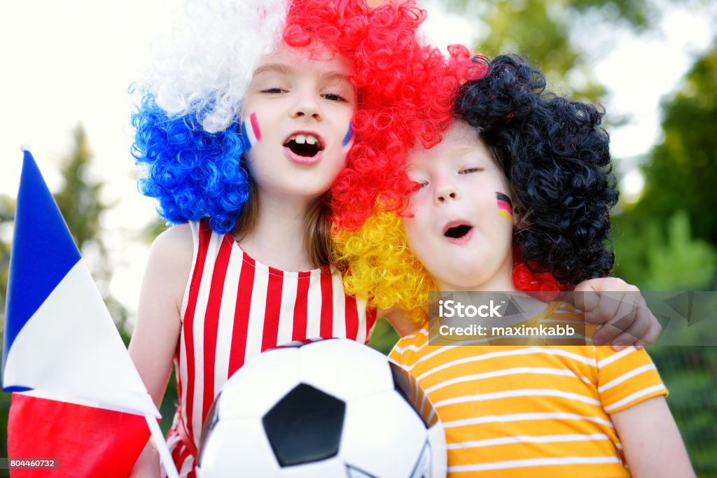 Two funny little sisters supporting and cheering their national football teams Two funny little sisters supporting and cheering their national football teams during soccer championship Child Stock Photo